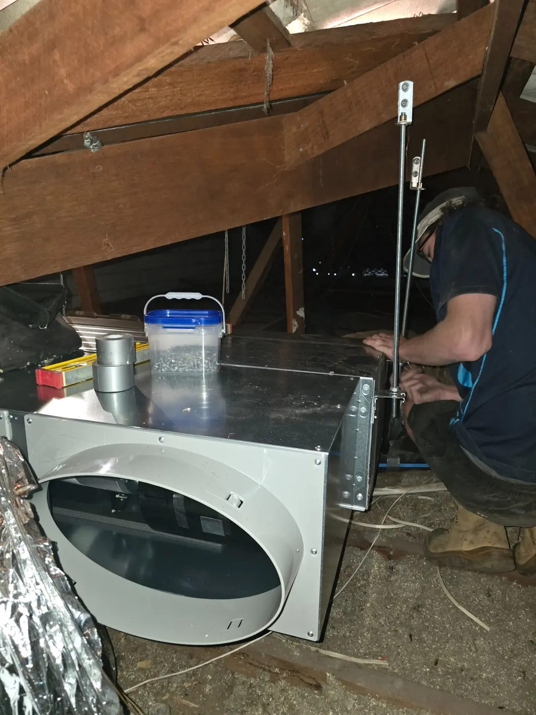 Big Chill technician installing ducted air conditioning equipment in a roof space